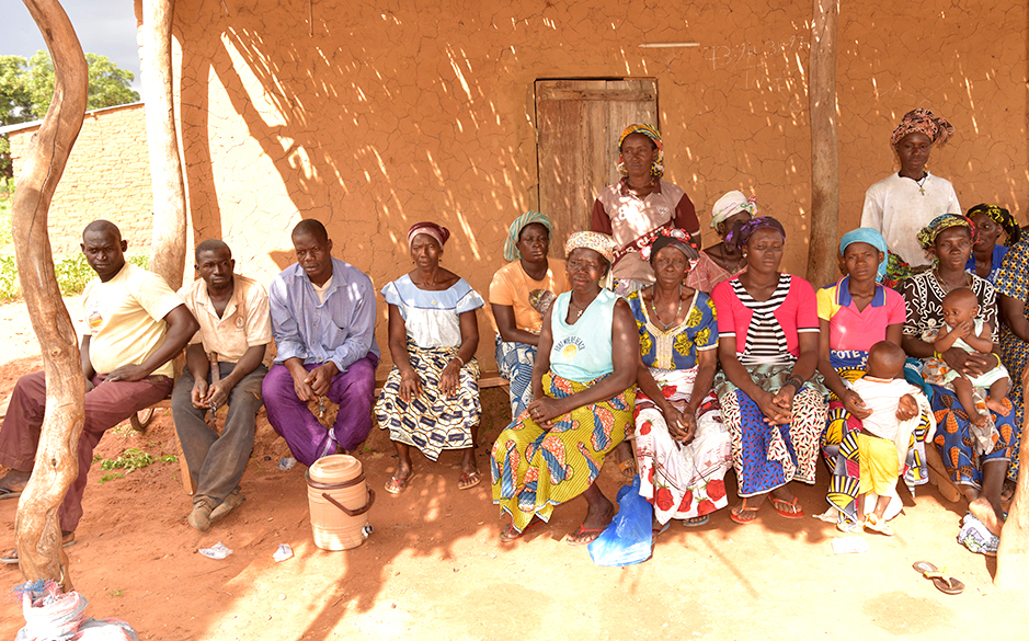 A group photo of people sitting outside a house in Africa